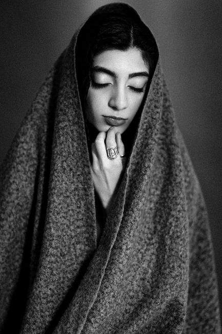Black and white portrait of a woman draped elegantly in a thick woolen blanket.