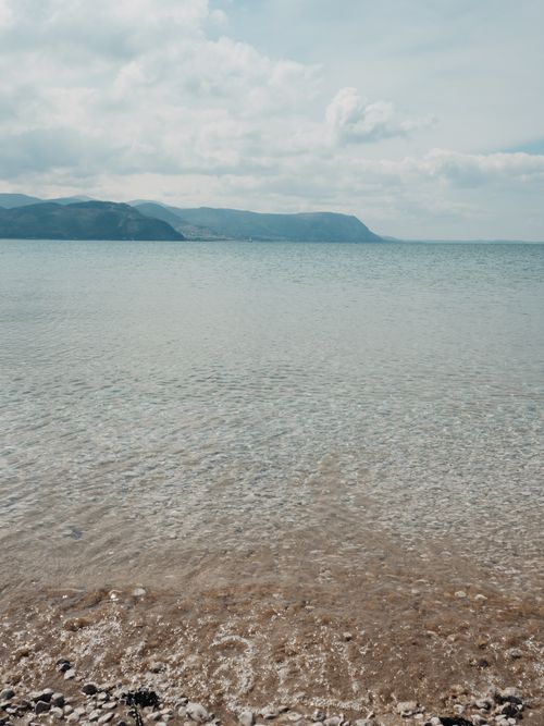 Free Serene and calm seashore view at Llandudno Beach in Wales with distant hills. Stock Photo
