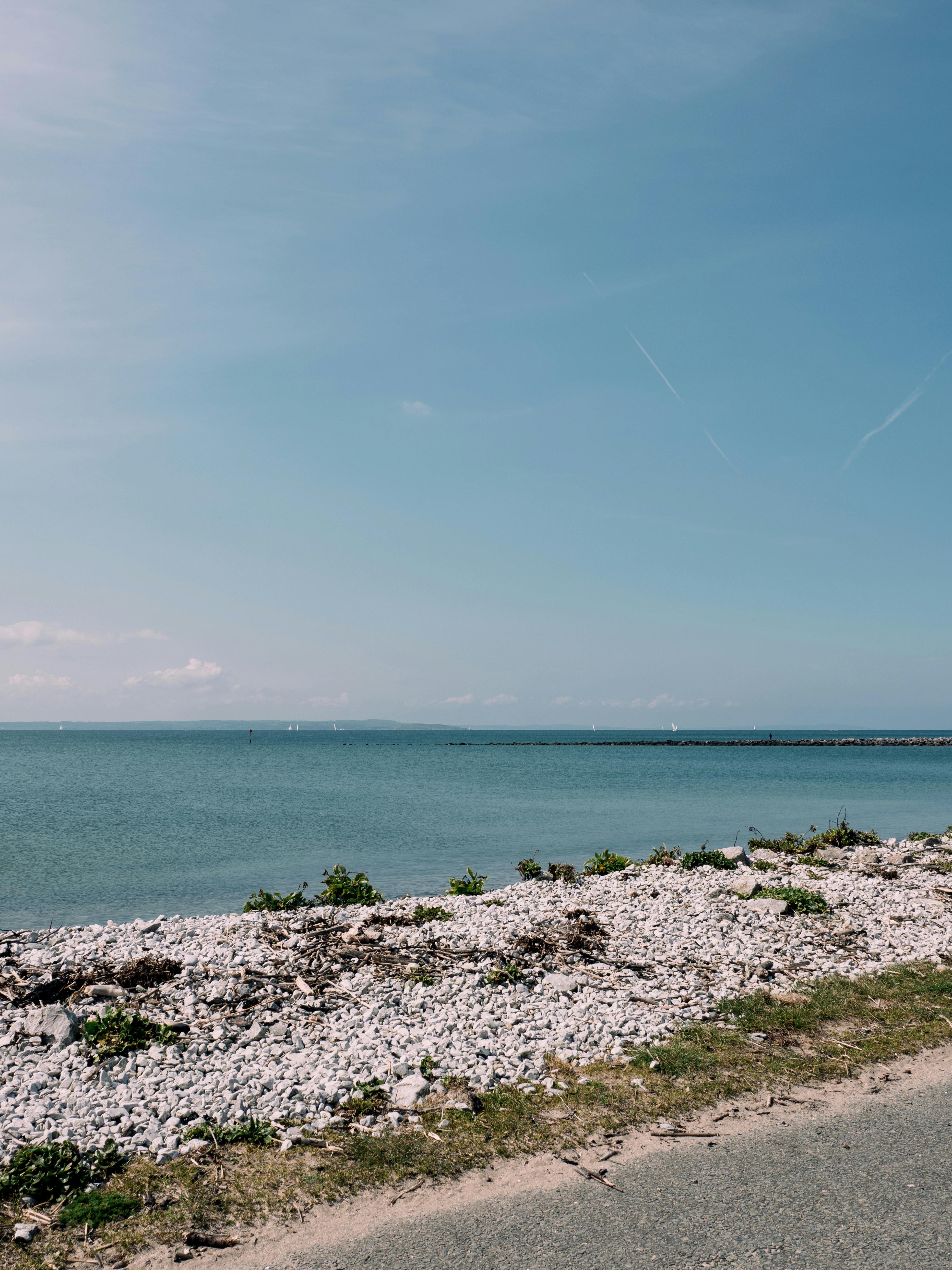 Tranquil summer day at the Llandudno coast, showcasing a calm blue sea and rocky shoreline.