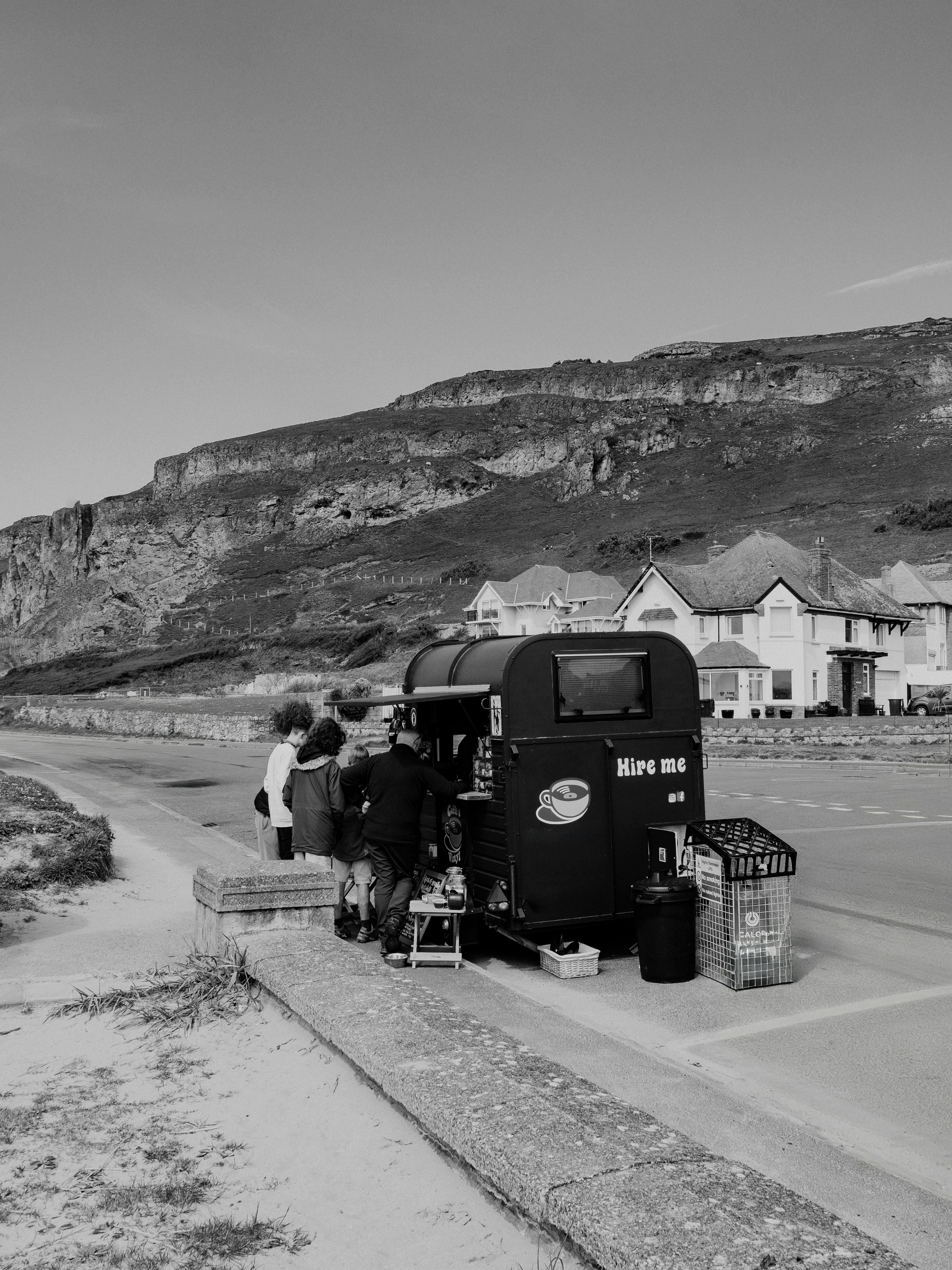 Charming roadside coffee stand with people enjoying a scenic backdrop in monochrome.