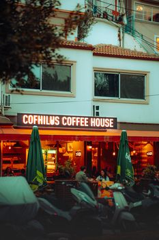 Cozy urban café scene at dusk with a lively atmosphere and people outside.