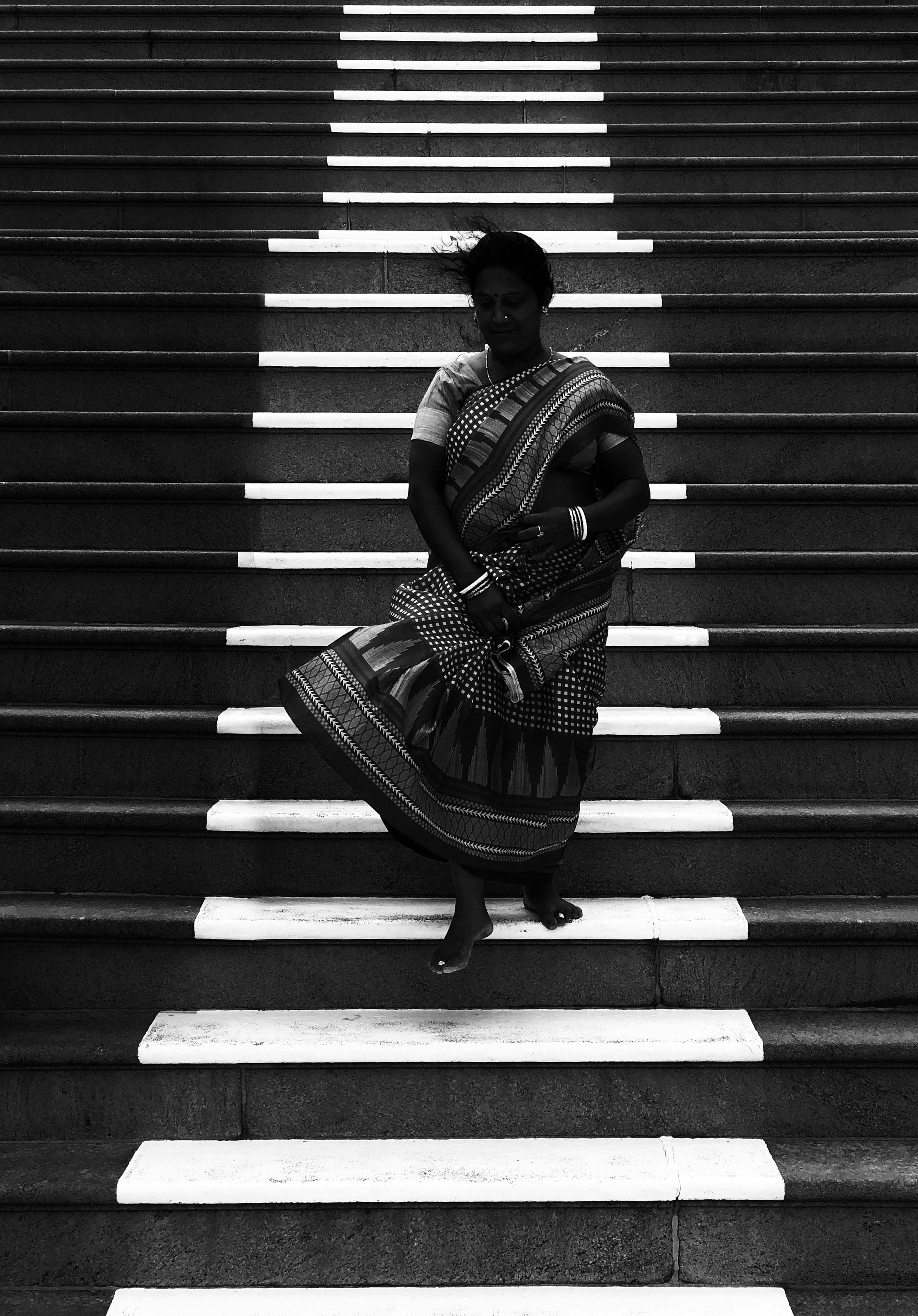 A woman in traditional attire stands barefoot on stairs in Kanniyakumari, India.