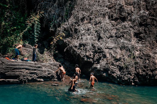 在越南邦玛图的天然游泳池里，一群孩子在岩石地形环绕中游泳、跳跃