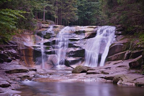 Free A tranquil waterfall cascading over rocks in a lush forest setting, ideal for travel and nature themes. Stock Photo
