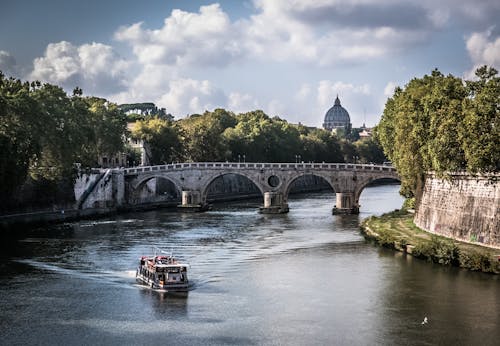 White Boat on Body of Water Crossing a Gray Concrete Bridge during Daytime