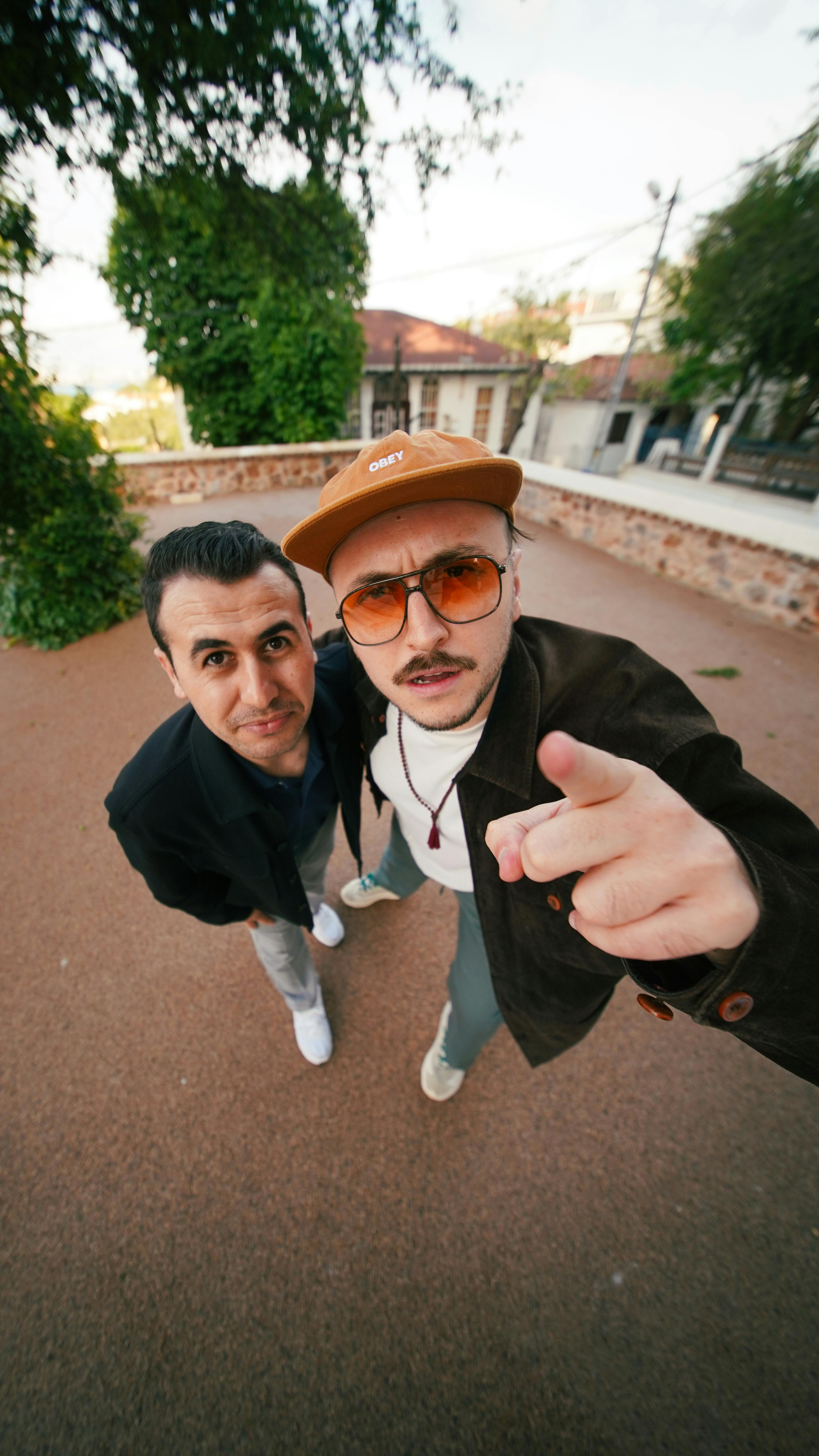 Two stylish men posing outdoors in İstanbul with a playful, modern vibe.