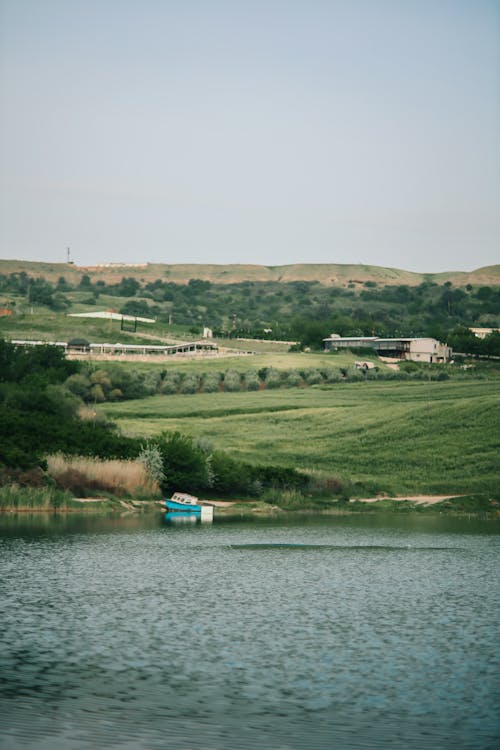 A boat is sitting on the water in front of a green field