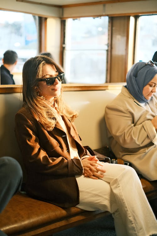 A woman sitting on a bus with sunglasses on