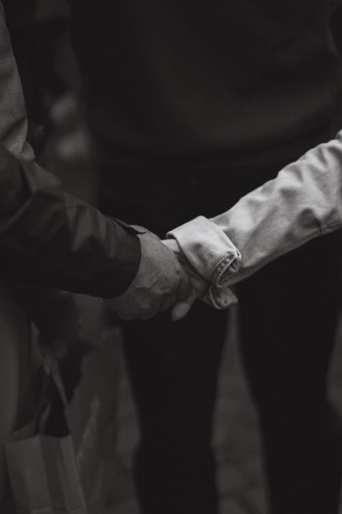 Free A close-up black and white photo capturing intimacy as two hands hold together tightly. Stock Photo