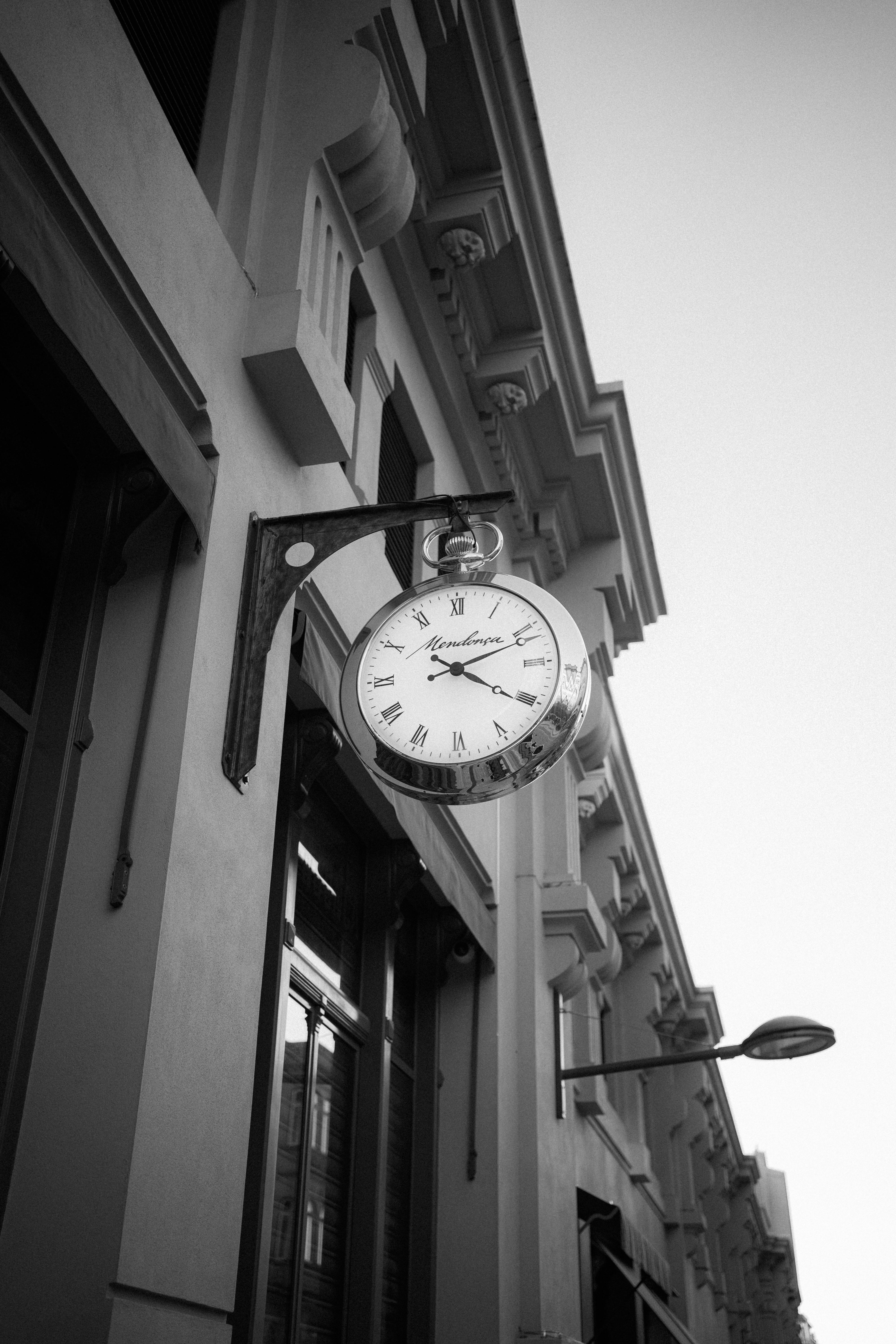 Low angle shot of a classic clock on a city building, monochrome style.