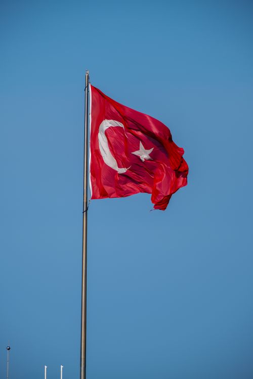 Free A vibrant Turkish flag waves against a clear blue sky, symbolizing national pride and identity. Stock Photo