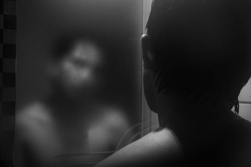 Free Black and white image of a shirtless man gazing at his reflection in a steamy mirror. Stock Photo