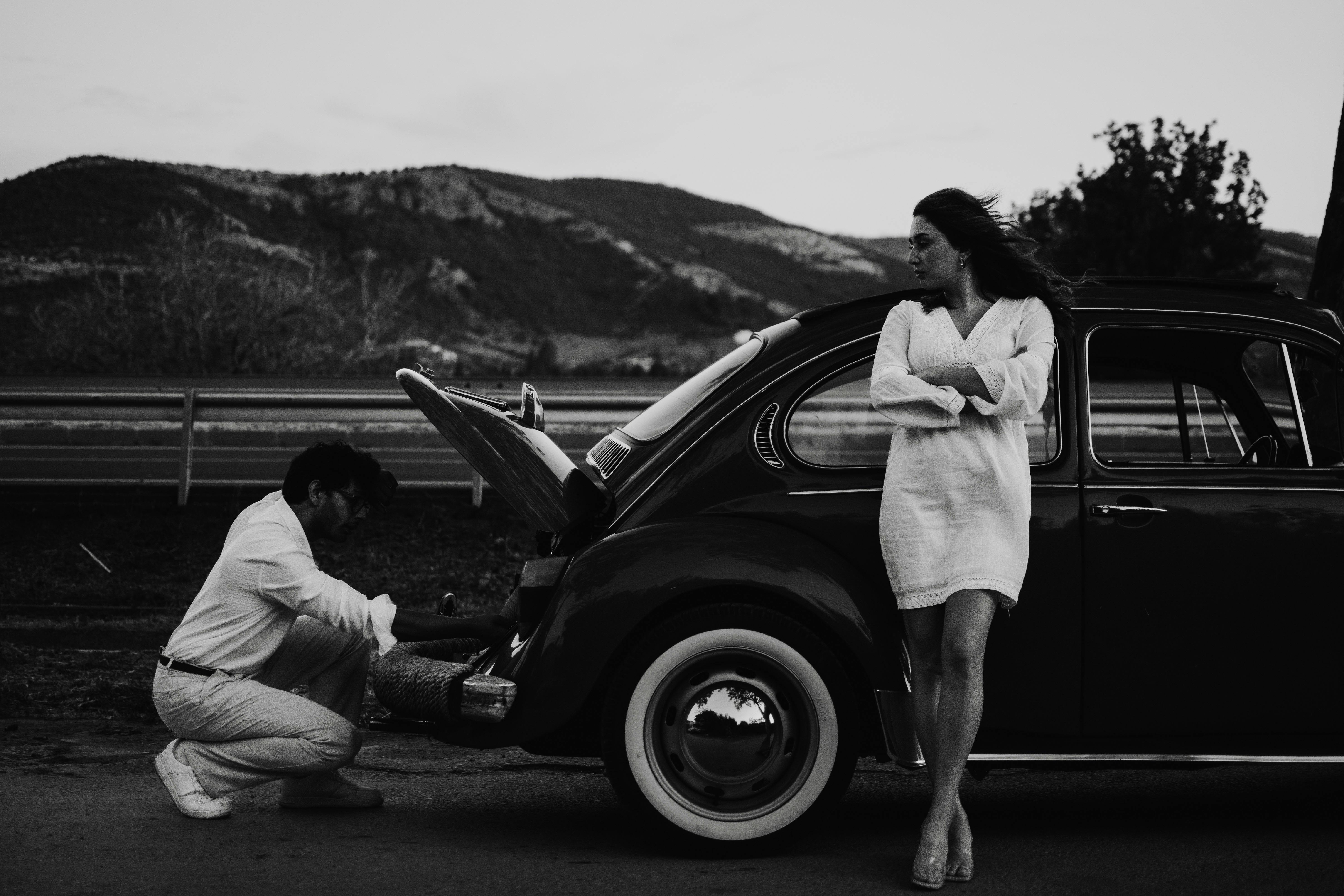 A couple with a vintage Volkswagen on a scenic road in Çanakkale, Türkiye.