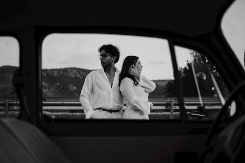 Woman and Man Standing behind Car Window