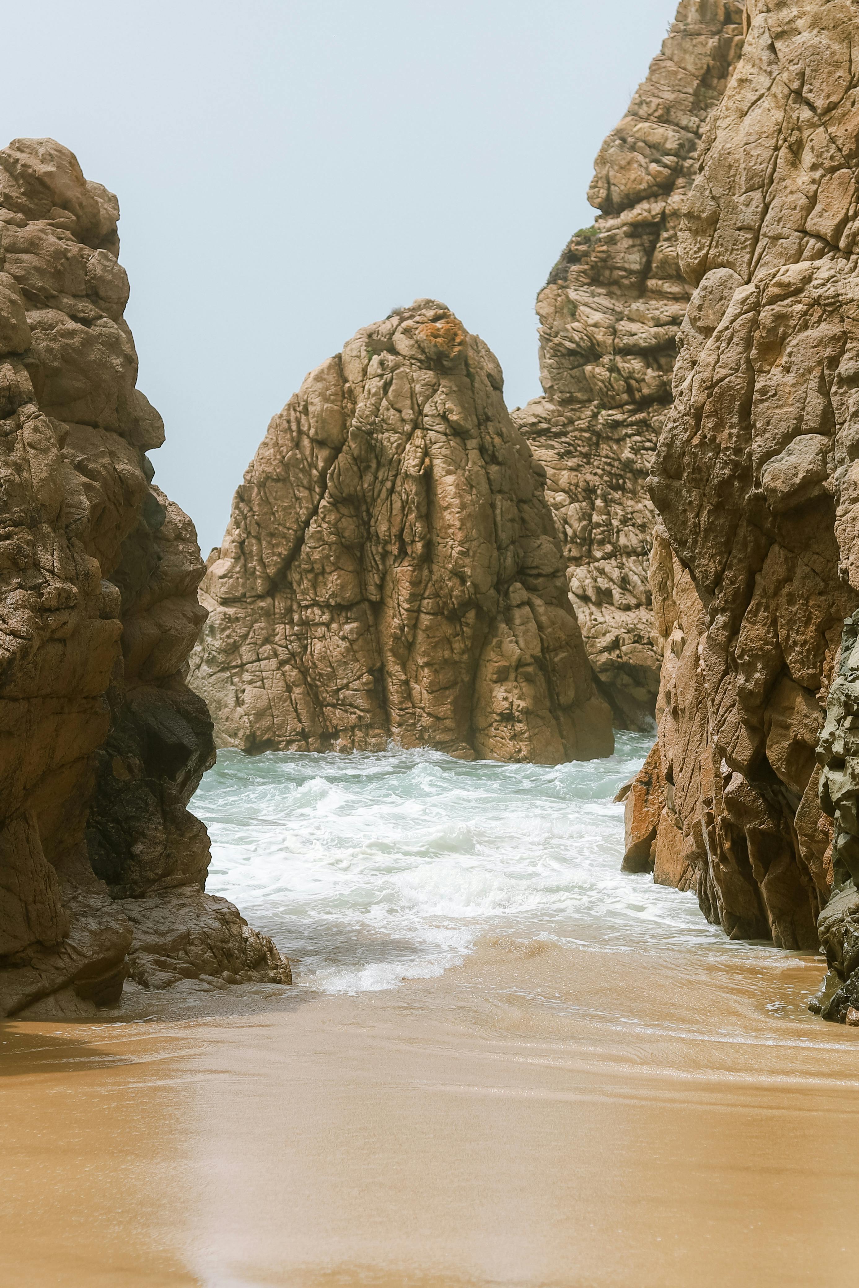Captivating view of dramatic rock formations along a sandy beach with crashing waves.