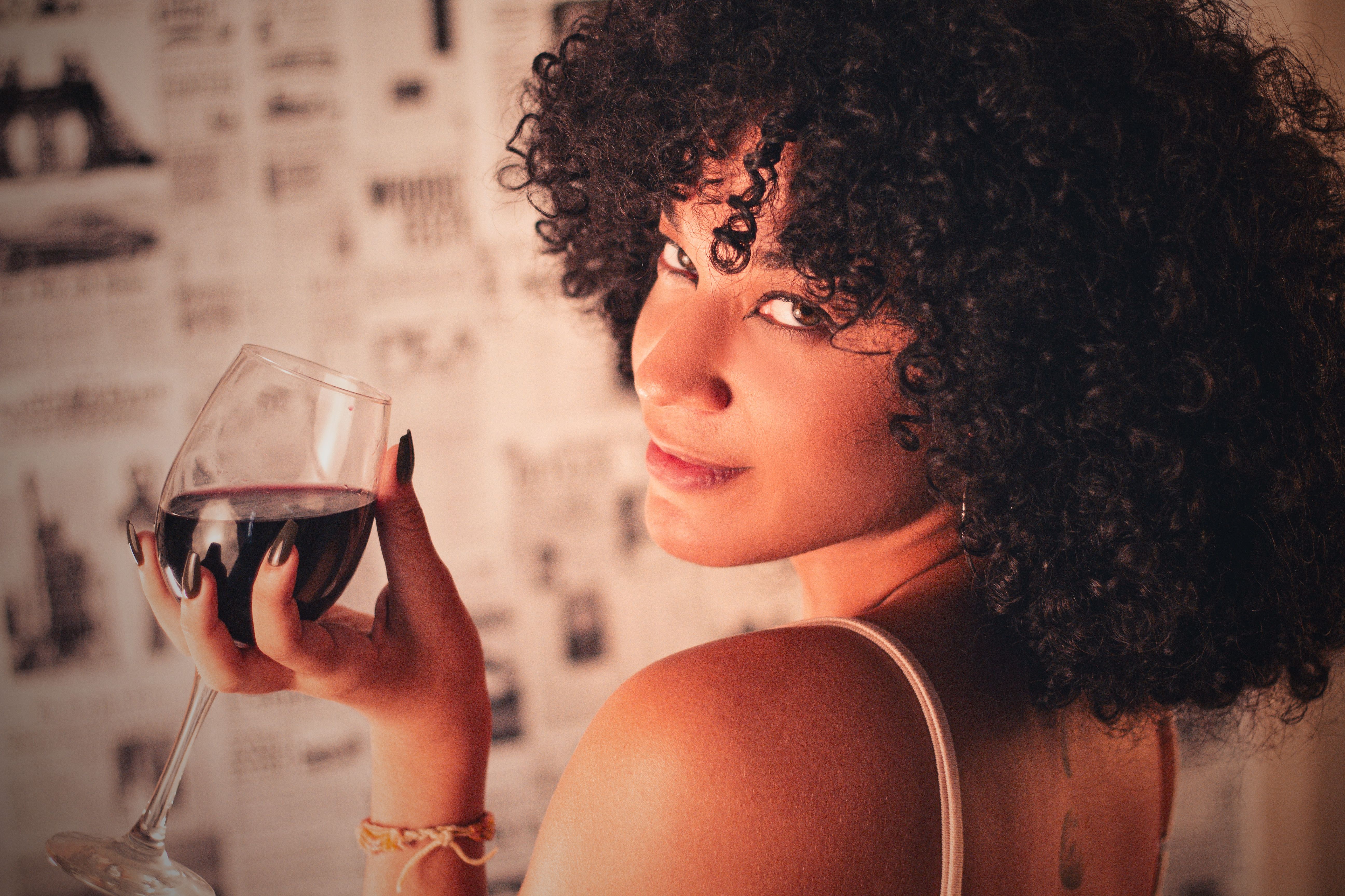 Young Woman Holding a Glass of Red Wine in her Hand · Free Stock Photo