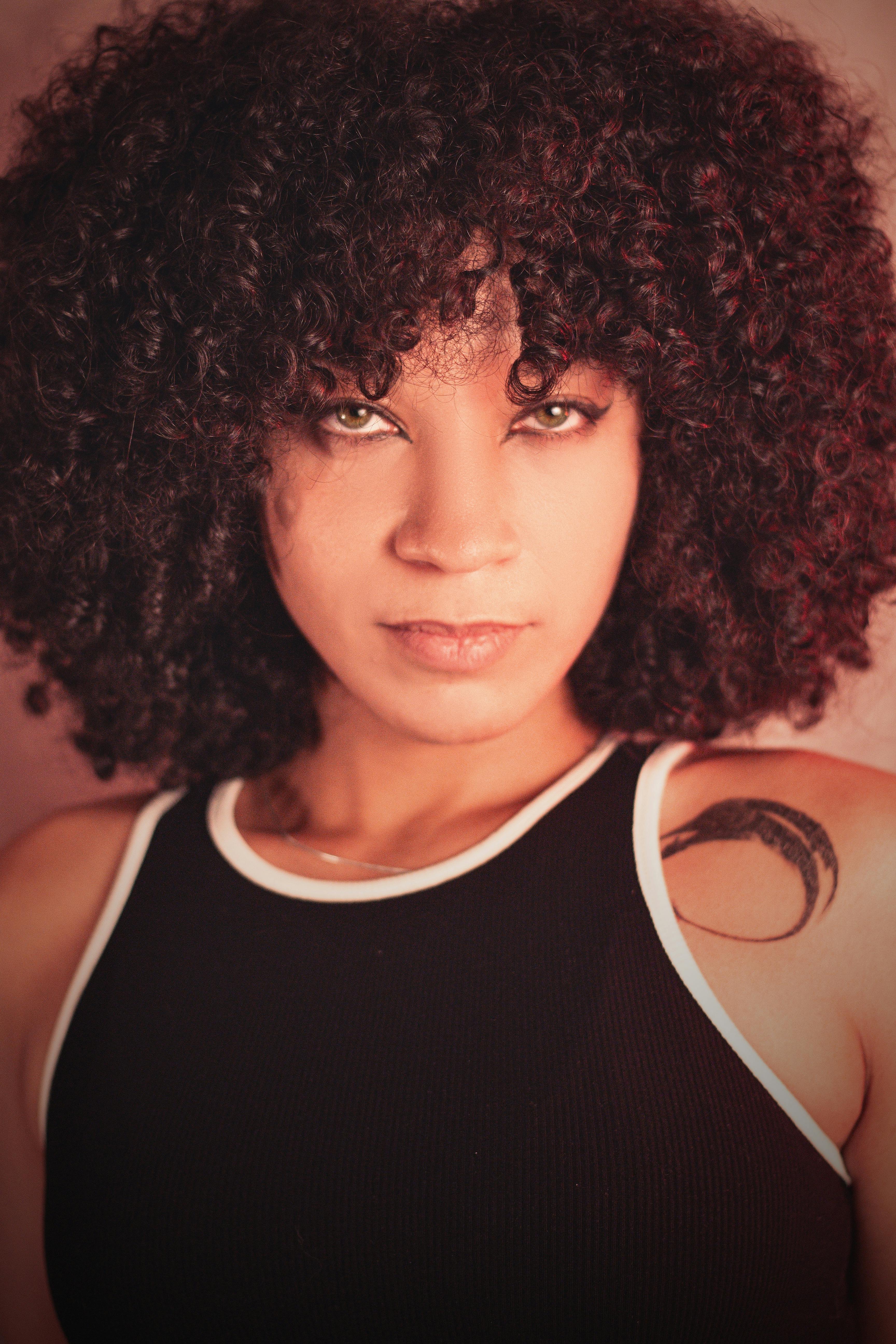 Stunning portrait of a woman with curly hair and a tank top, showcasing modern fashion.