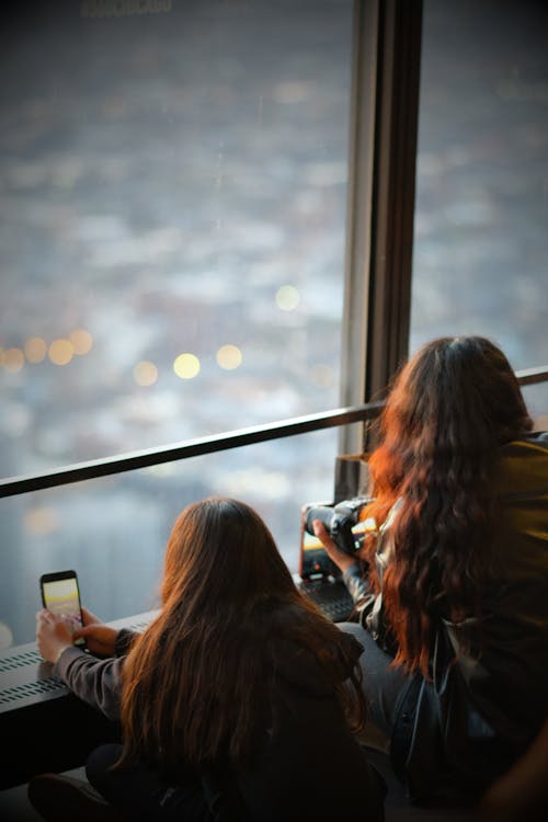 Two women looking at a city from a window