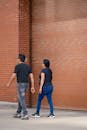 A couple walking down the street in front of a brick building