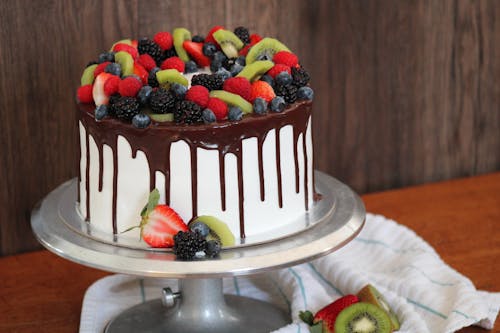 A cake with fruit and chocolate drizzled on top
