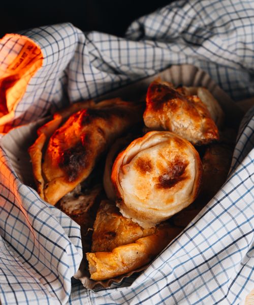 Free A close-up of freshly baked empanadas wrapped in a cloth, showcasing a warm, homemade feel. Stock Photo