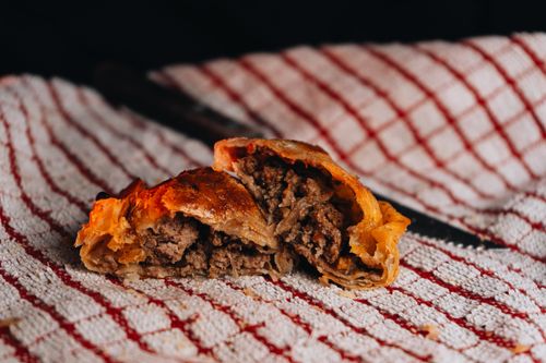 Free Close-up of a meat-filled Argentine empanada on a textured cloth, showcasing local culinary traditions. Stock Photo