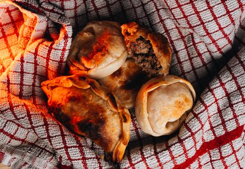 Free Close-up of Argentine empanadas on a red checked cloth, highlighting their golden crust. Stock Photo