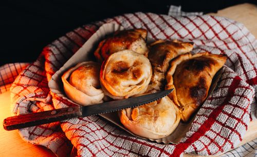 Free Close-up of freshly baked empanadas on a red and white cloth with a knife. Stock Photo