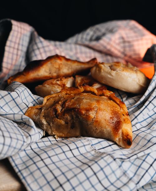 Free Warm Argentinian empanadas on a checkered cloth, capturing a rustic culinary scene. Stock Photo