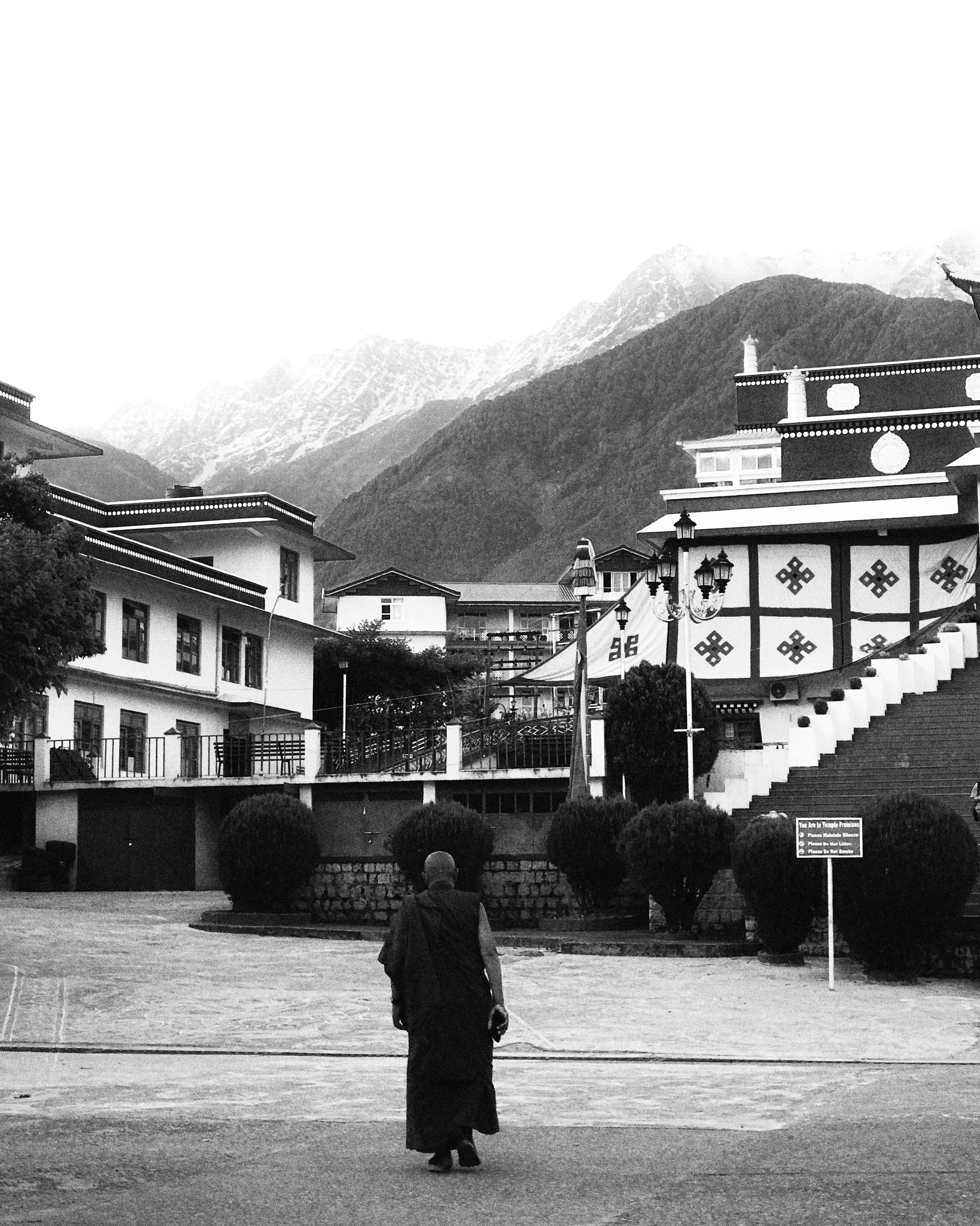 Monk walking towards traditional Tibetan architecture in Himalayan village.