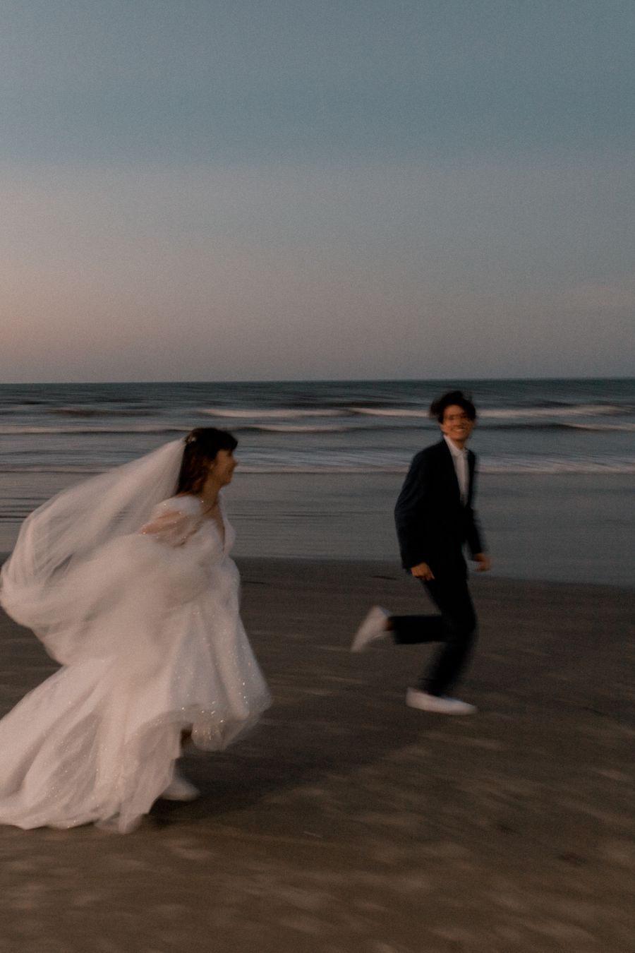 Los novios corren por la playa al anochecer (fotografía de referencia)