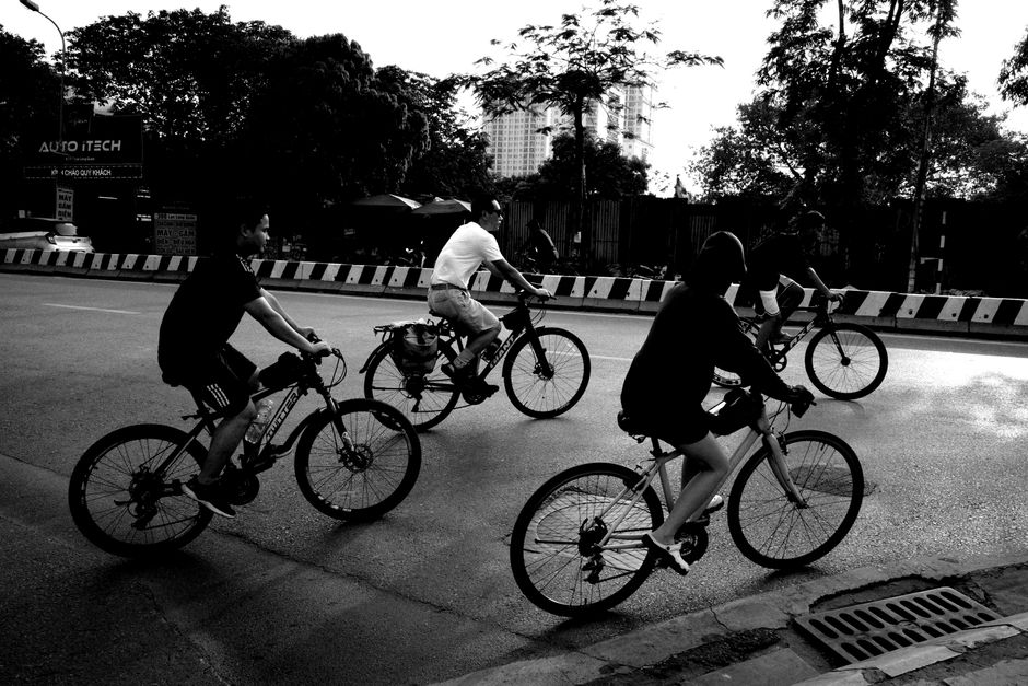 A group of people cycling on an urban road captured in a black and white photograph.