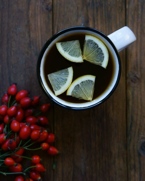 Free Close-up view of a herbal tea with lemon slices and red berries on a rustic wooden table. Stock Photo