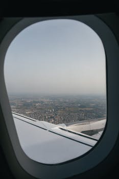 View of Israeli cityscape through airplane window during flight, showcasing the vast city below.