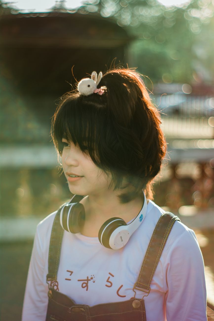 Charming portrait of a young woman with headphones and a cute hair accessory, enjoying a sunny day o