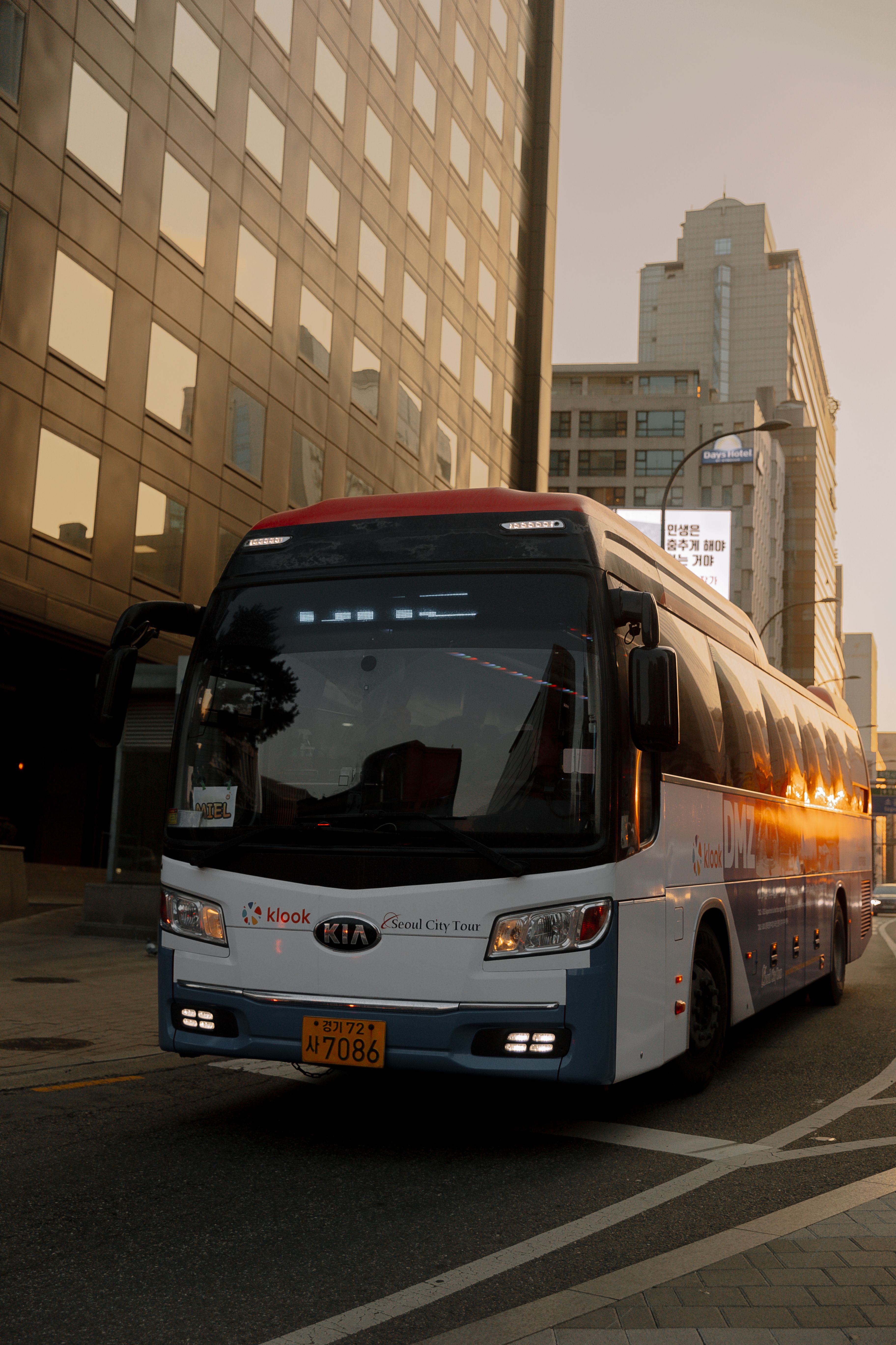 A city bus travels through urban streets at sunset, reflecting a modern city vibe.