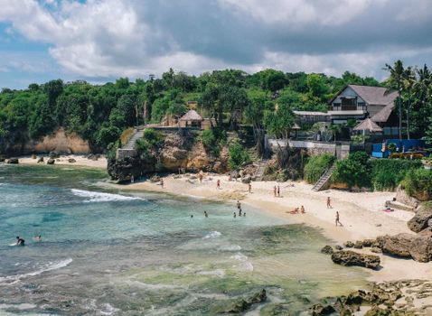 A picturesque beach scene in Bali, featuring white sand, lush greenery, and clear turquoise waters.