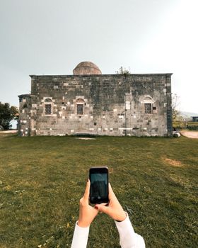 Smartphone capturing a historic building in a rural setting, emphasizing travel and architecture.
