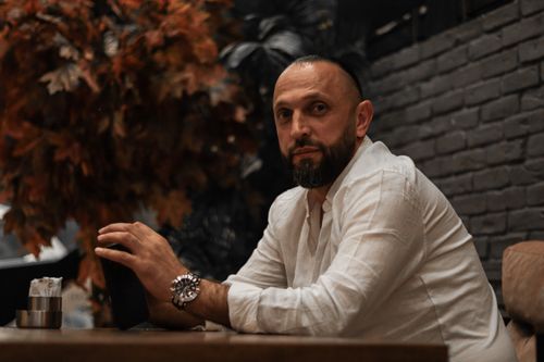 Free Portrait of a thoughtful man sitting at a table in a warm, indoor setting with autumnal decor. Stock Photo