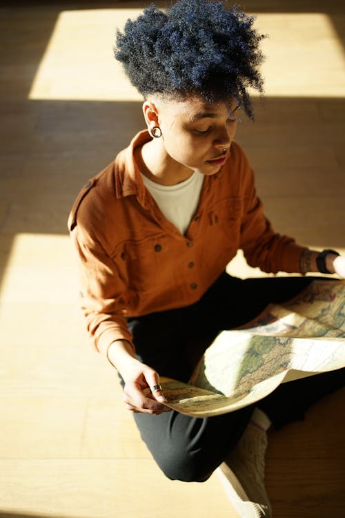 A woman with an afro sitting on the floor looking at a map