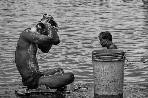 Free Two men washing by the river in Kolkata, India, on a sunny day. Stock Photo