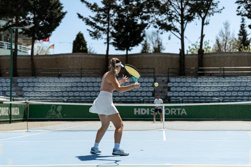 A woman in white tennis outfit playing tennis