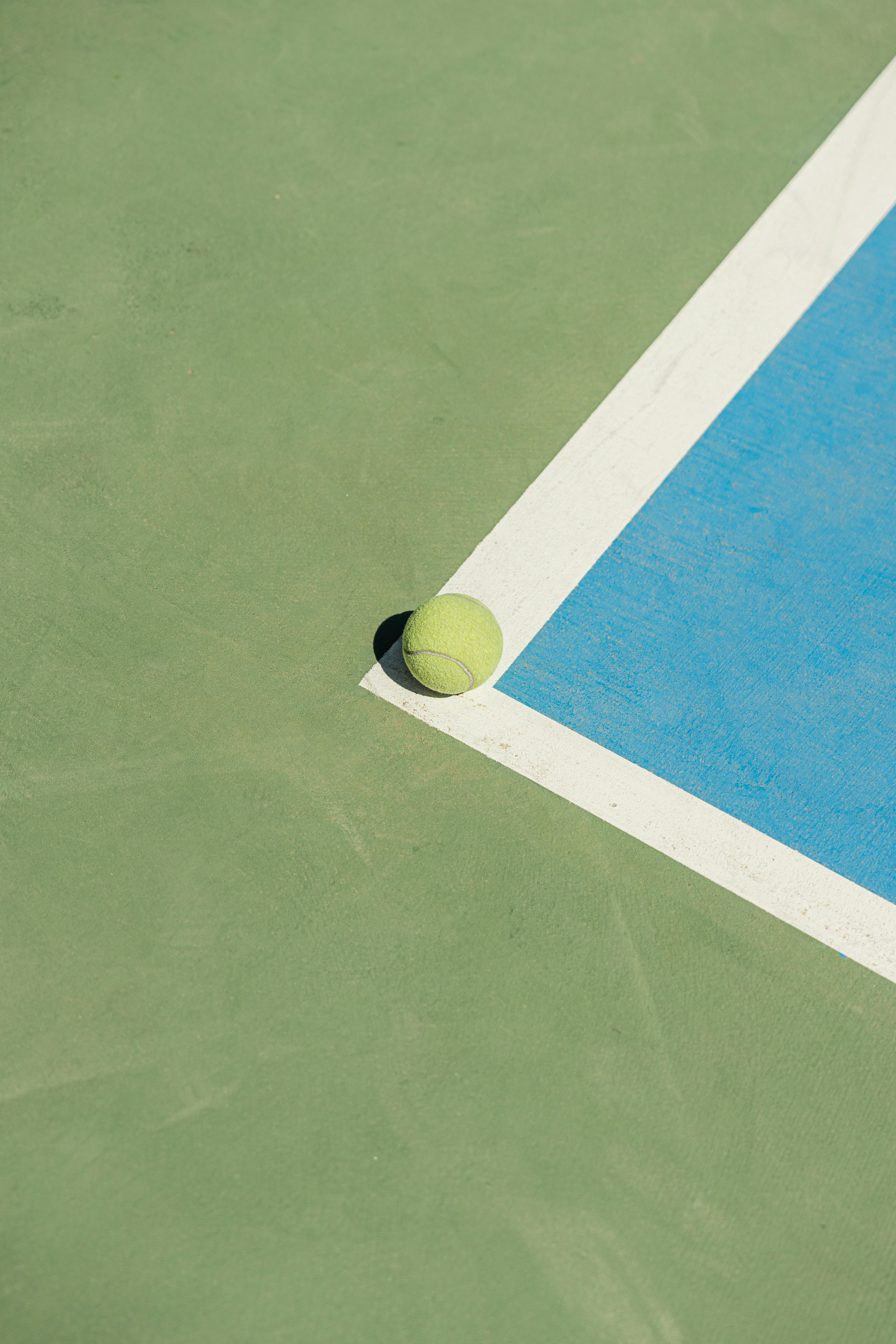 Free A tennis ball rests on the court corner, highlighting sports action and precision. Stock Photo