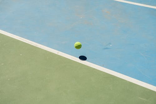 A tennis ball on a green and blue tennis court
