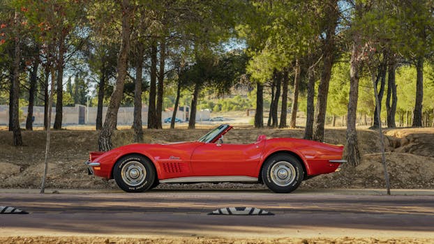 A stunning vintage red Chevrolet cabriolet in an outdoor forest setting, showcasing classic car beauty.