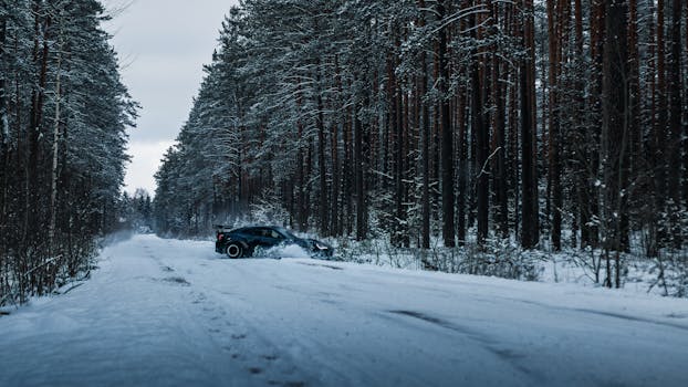 A sleek sports car drifting on a snowy road surrounded by a serene evergreen forest in winter.