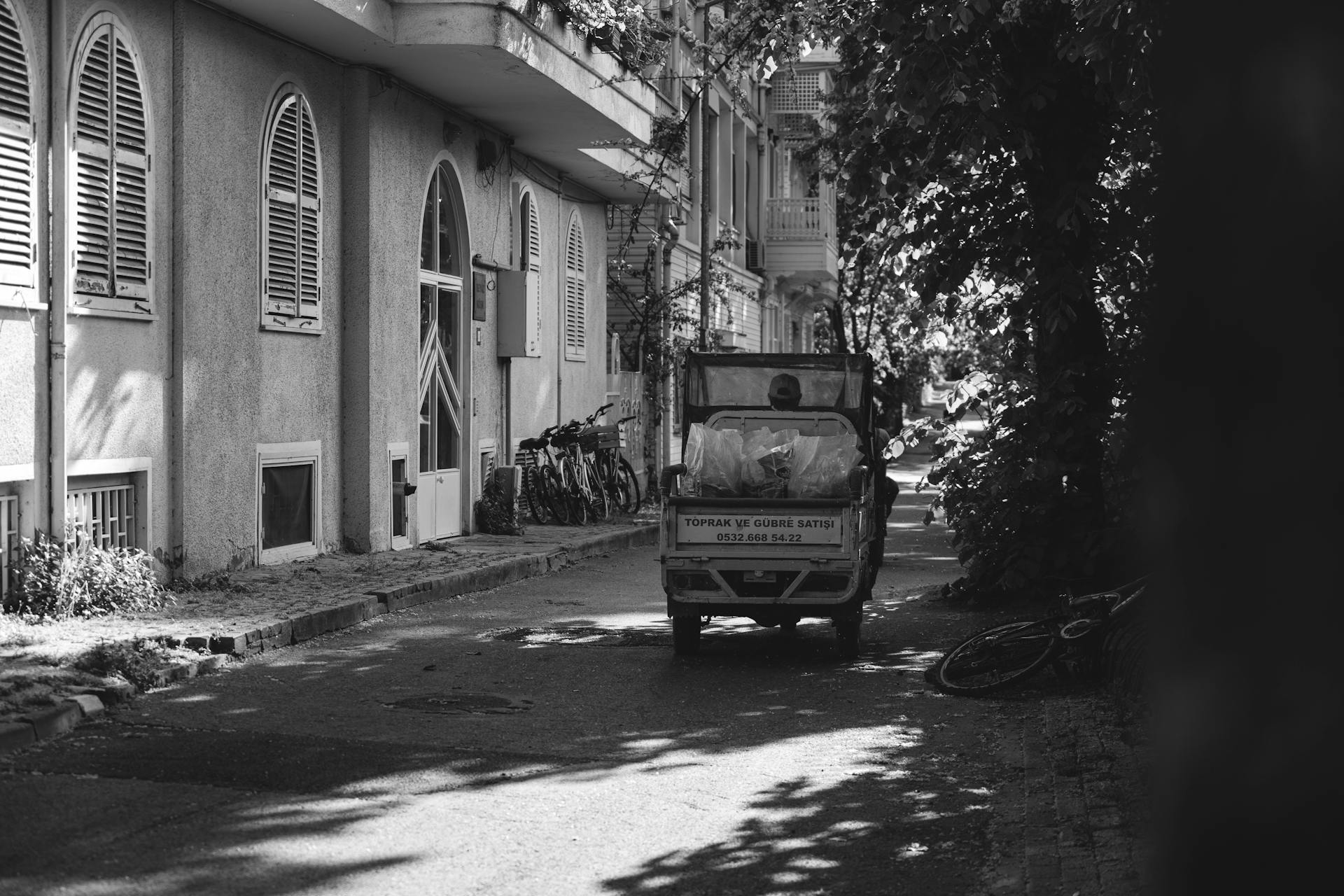 Monochrome image of a quiet city street with a small truck and bicycles.