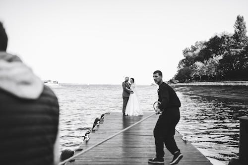 A bride and groom are standing on a dock