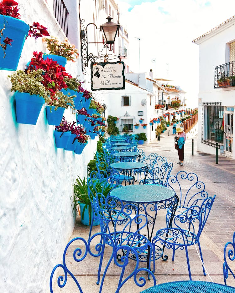 Blue Metal Bistro Sets Near Potted Flowers And Road