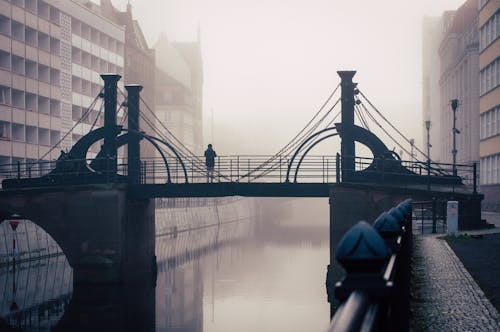 A bridge in the fog with a person walking on it